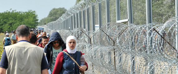 Migrants and refugees walk near razor-wire along a 3-meter-high fence at the official border crossing between Serbia and Hungary, near the northern Serbian town of Horgos on September 15, 2015. Hungary effectively sealed its border with Serbia on September 15 to stem the massive influx of refugees as Germany slammed the "disgraceful" refusal of other EU countries to accept more migrants after 22 died in yet another shipwreck. AFP PHOTO / ELVIS BARUKCIC